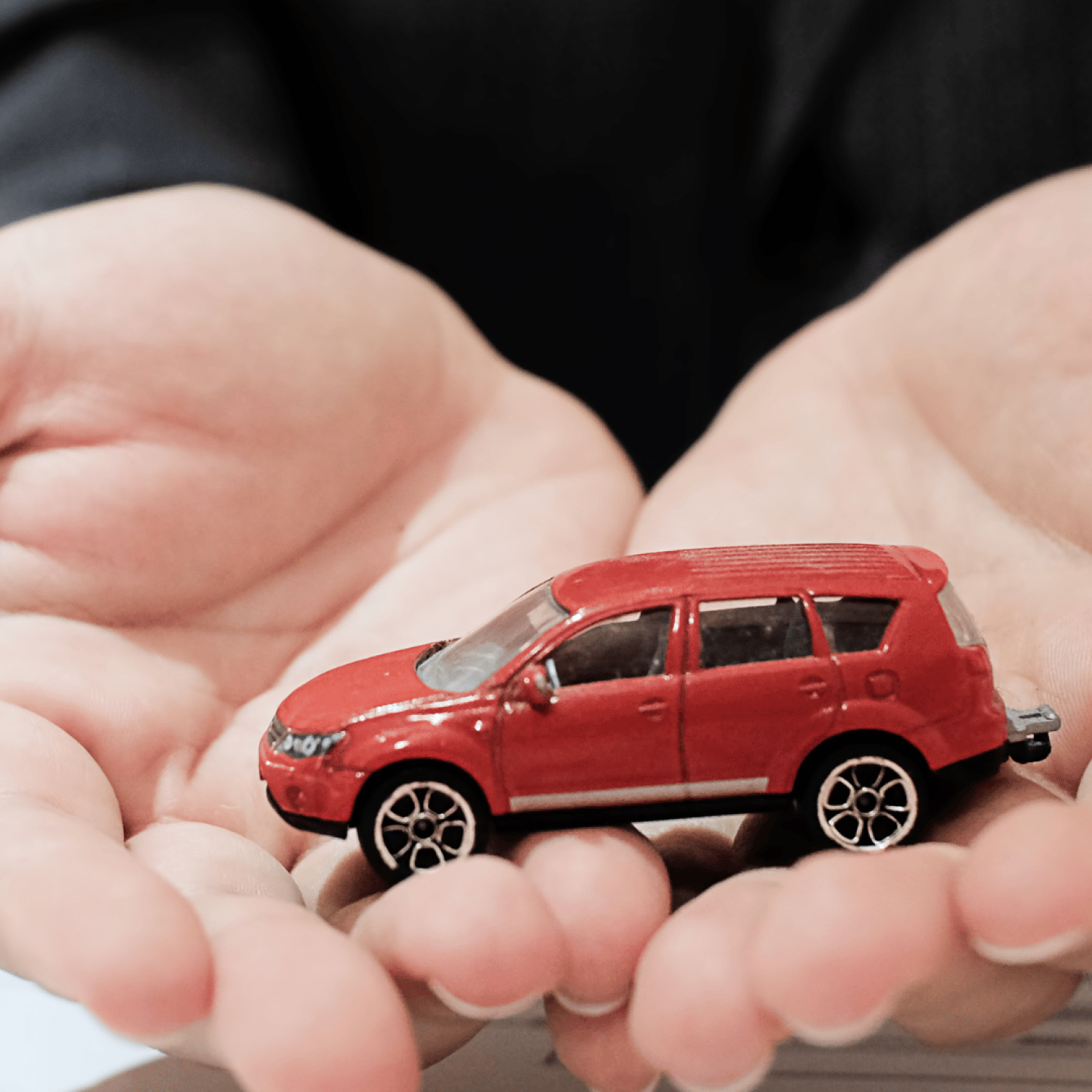 Carro vermelho nas mãos de uma pessoa, relacionando com a proteção veicular.