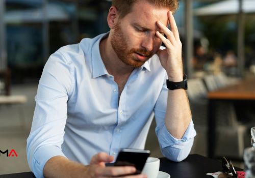 Homem com o celular nas mãos e com aparência preocupada